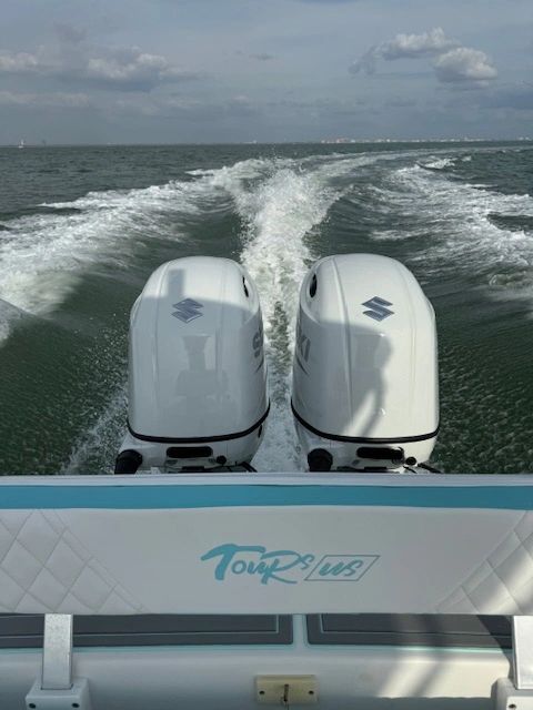 Two Suzuki outboard motors creating wake on ocean